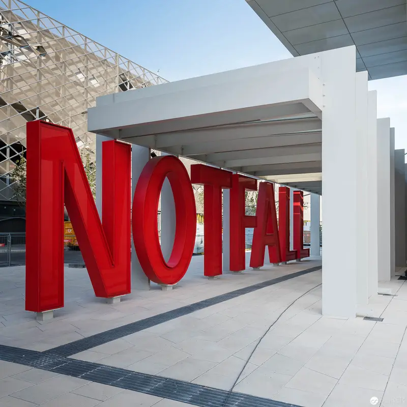 Monumental Red Typography Installation at Architectural Site with Dramatic Spatial Design