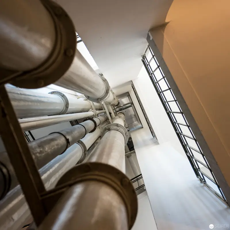 Architectural Perspective of Vertical Industrial Piping and Stairwell Interior