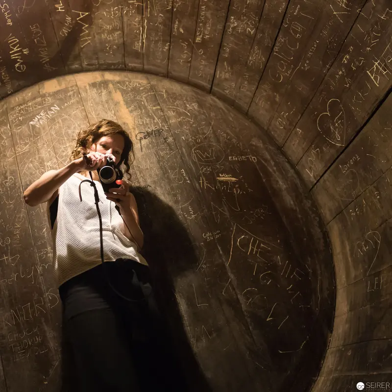 Photographer in Curved Tunnel with Graffitied Walls and Dramatic Lighting