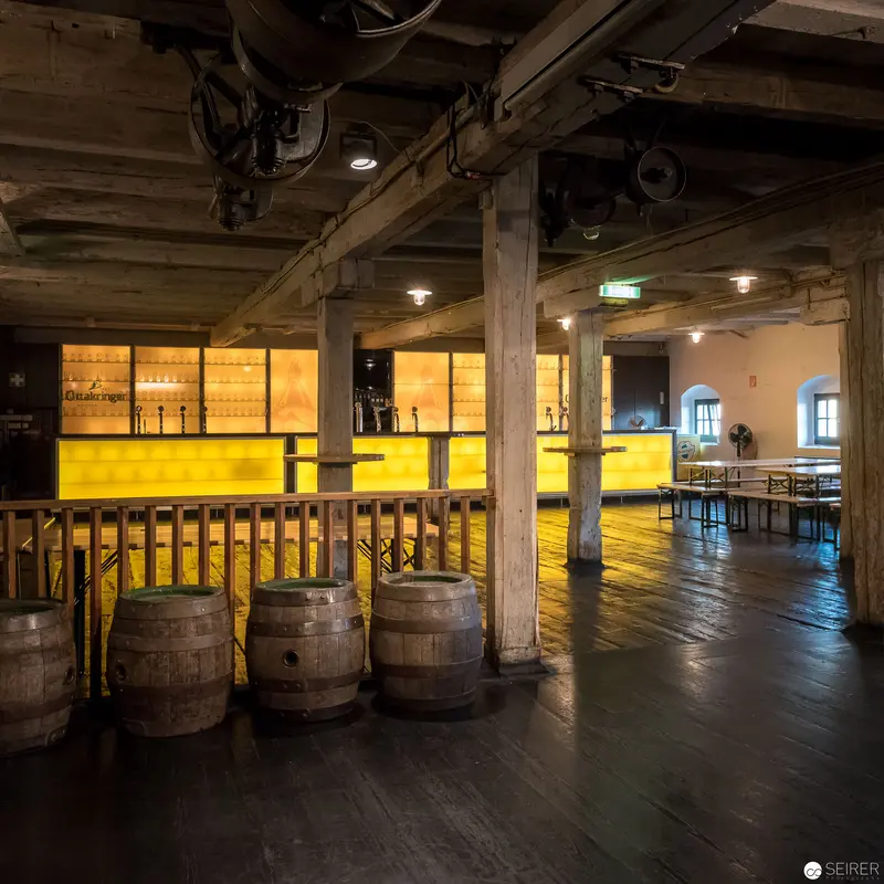 Industrial Brewery Interior with Wooden Barrels and Illuminated Yellow Bar