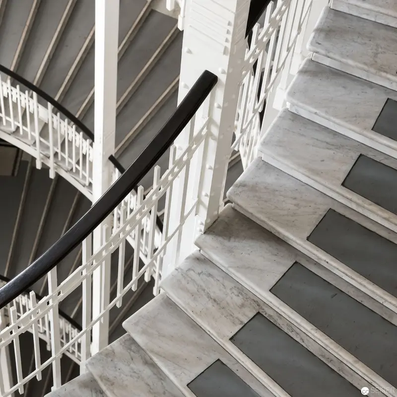 Geometric Monochrome Staircase with Marble Steps and White Lattice Railings