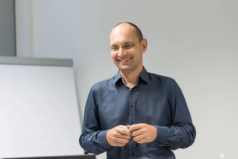 Smiling Professional at Microsoft User Group Meeting Adjusts Shirt Button