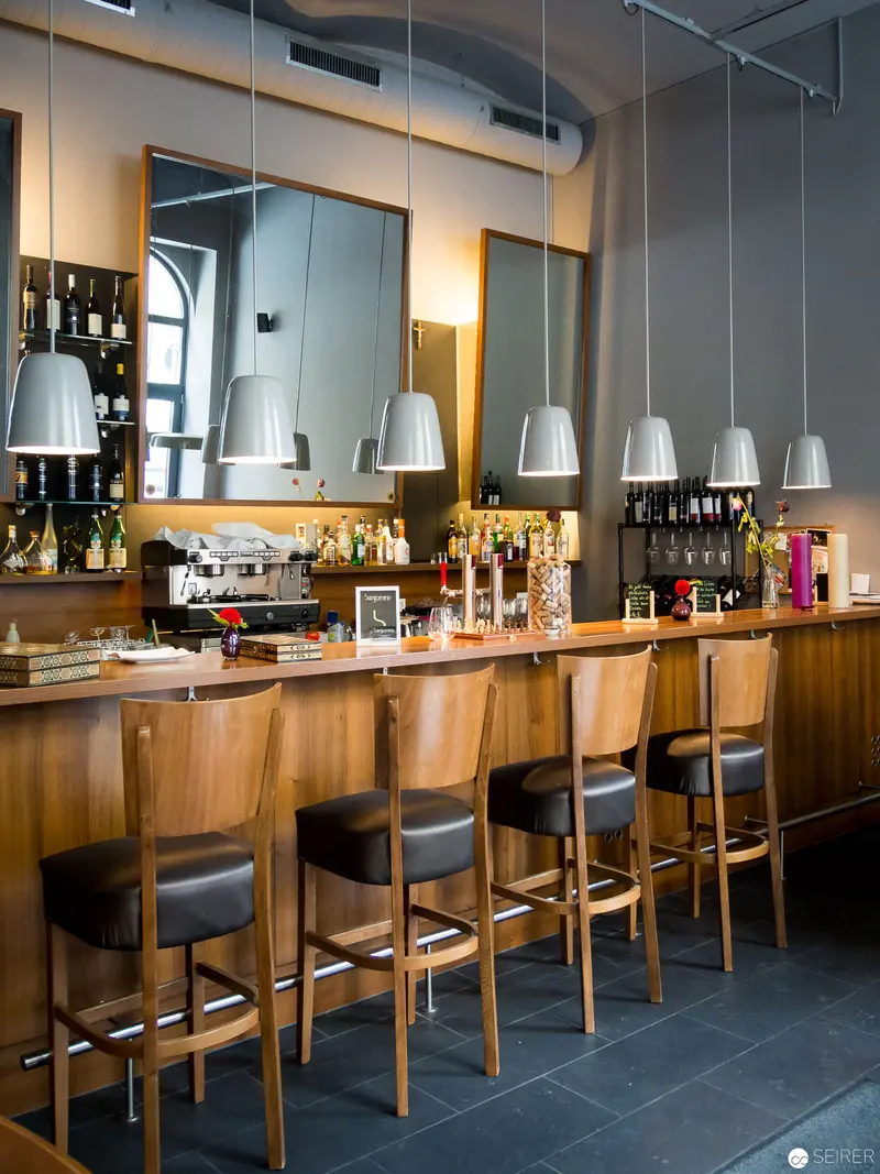 Contemporary Viennese Bar Interior with Suspended Lighting and Wooden Seating