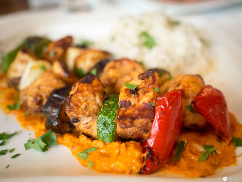 Grilled Meat Skewers with Roasted Vegetables on Vibrant Orange Sauce