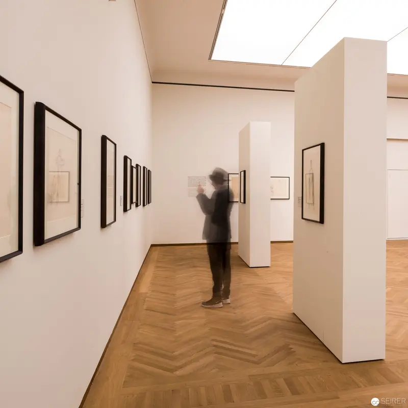 Gallery Interior with Lone Viewer Contemplating Framed Artworks in White Space