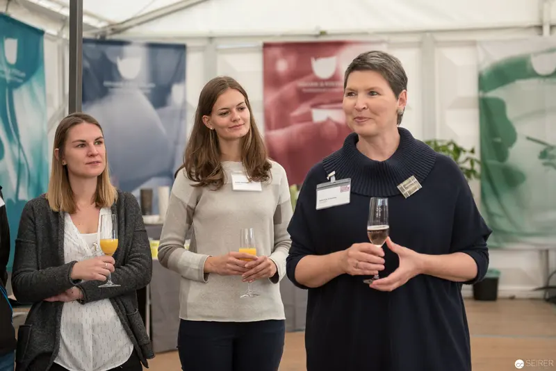 Professional Networking Event: Three Women with Beverages in White Tent