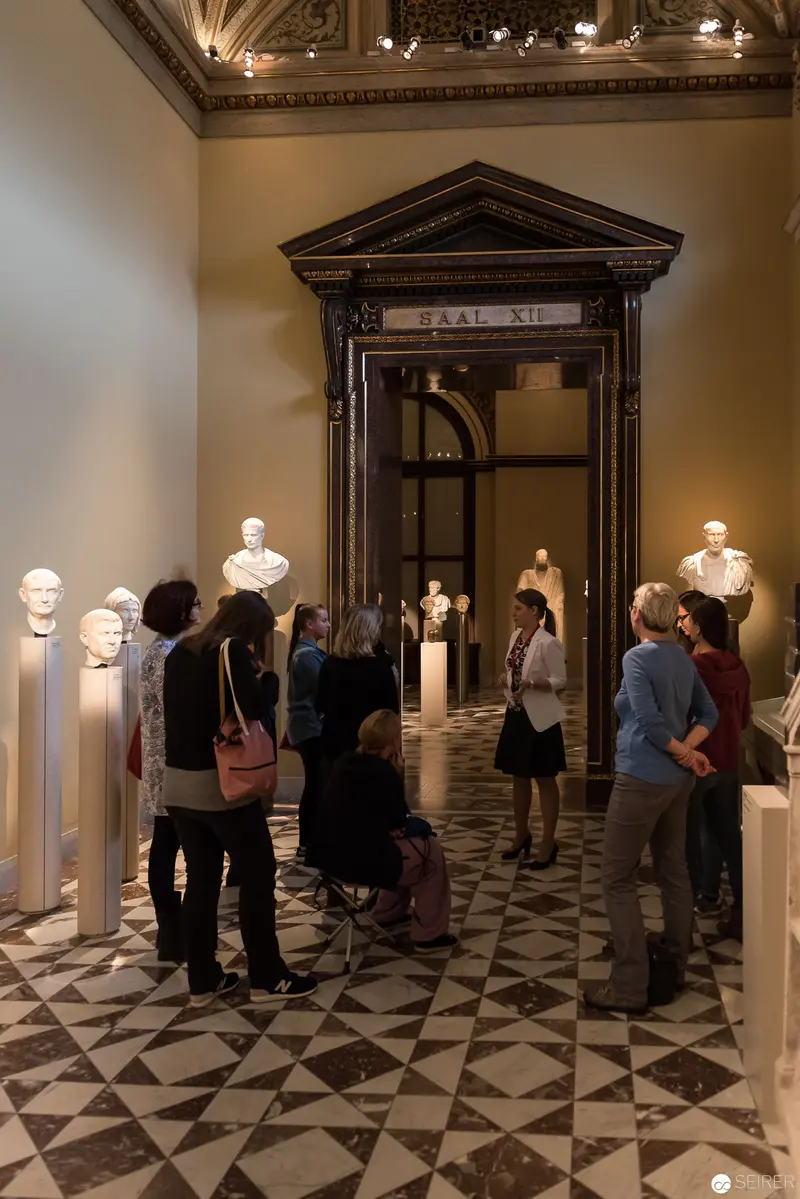 Museum Gallery Interior with Classical Marble Busts and Visitor Exploration