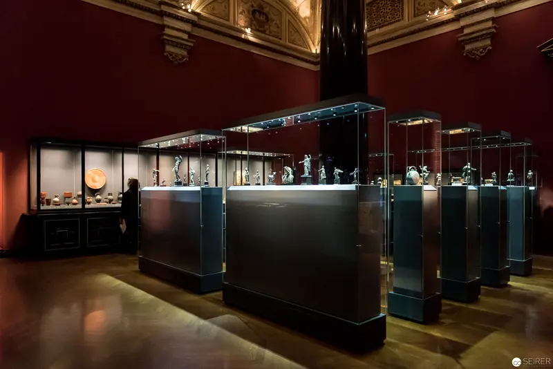 Museum Exhibition with Illuminated Glass Display Cases in Historic Interior