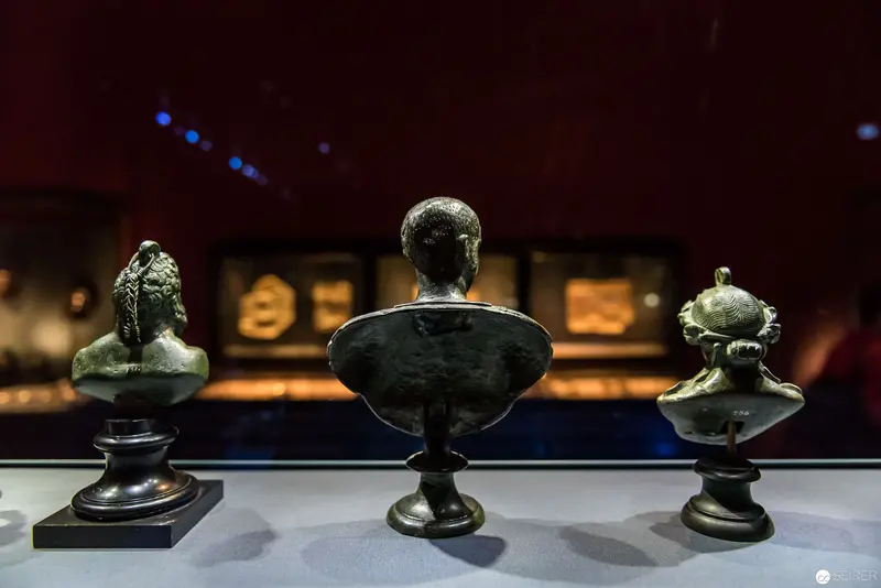 Three Sculptural Bronze Busts Displayed in Museum Exhibition Lighting