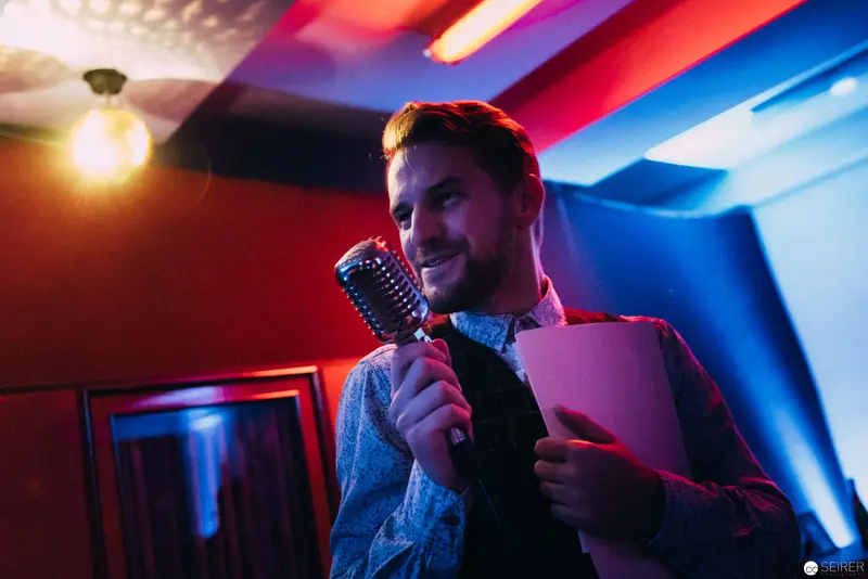 Performer with Vintage Microphone During Nesterval's "Dirty Faust" Theatre Production