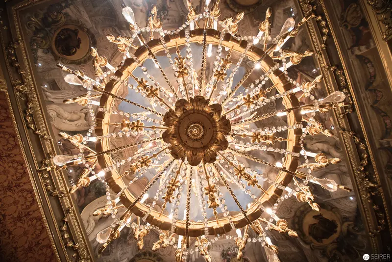 Baroque Crystal Chandelier Illuminating Ornate Ceiling at Vienna's Winter Palace