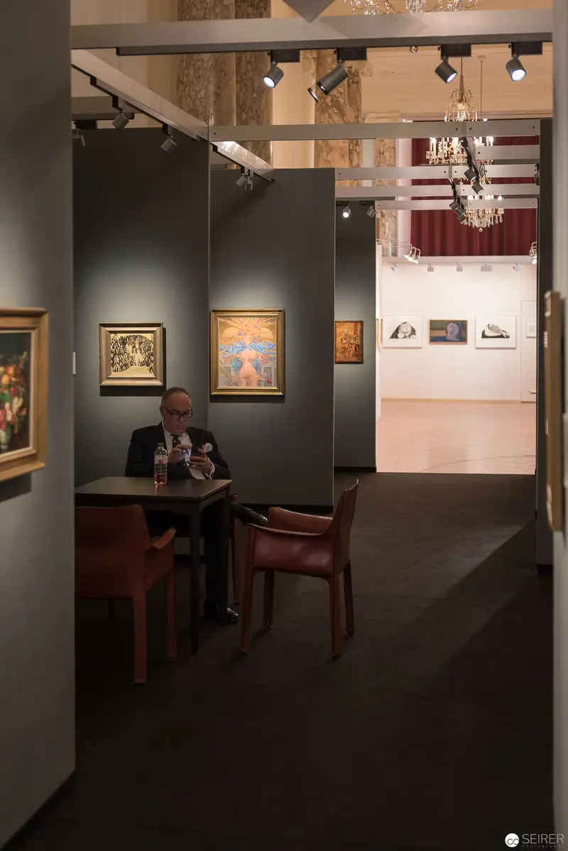 Art & Antique Fair Vienna: Scholarly Figure Seated in Gallery Space with Paintings