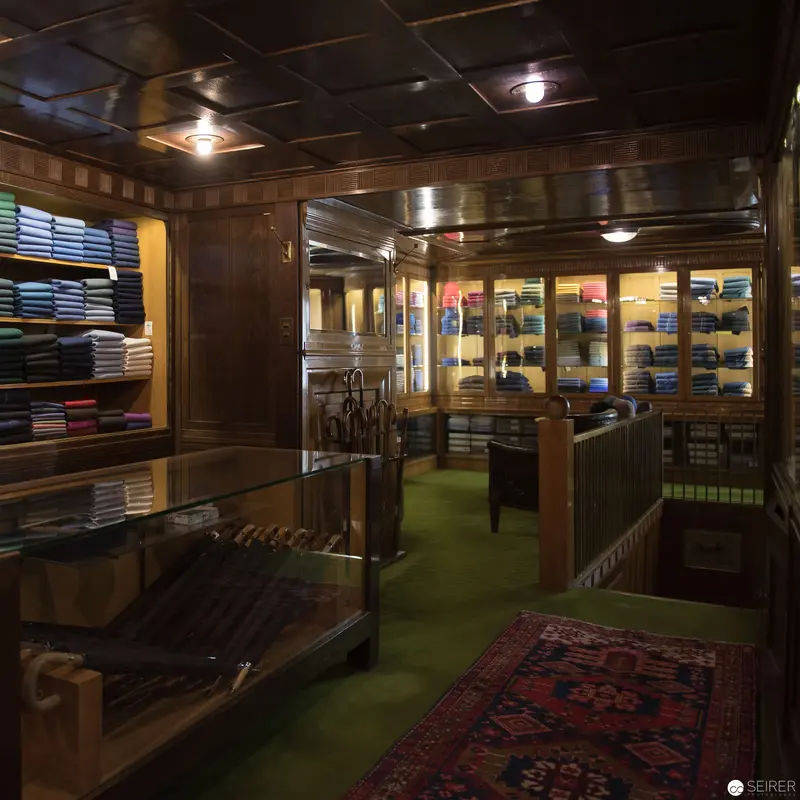 Rudolf Niedersüß's Elegant Knize Mode-Atelier Interior with Wooden Displays and Green Carpet