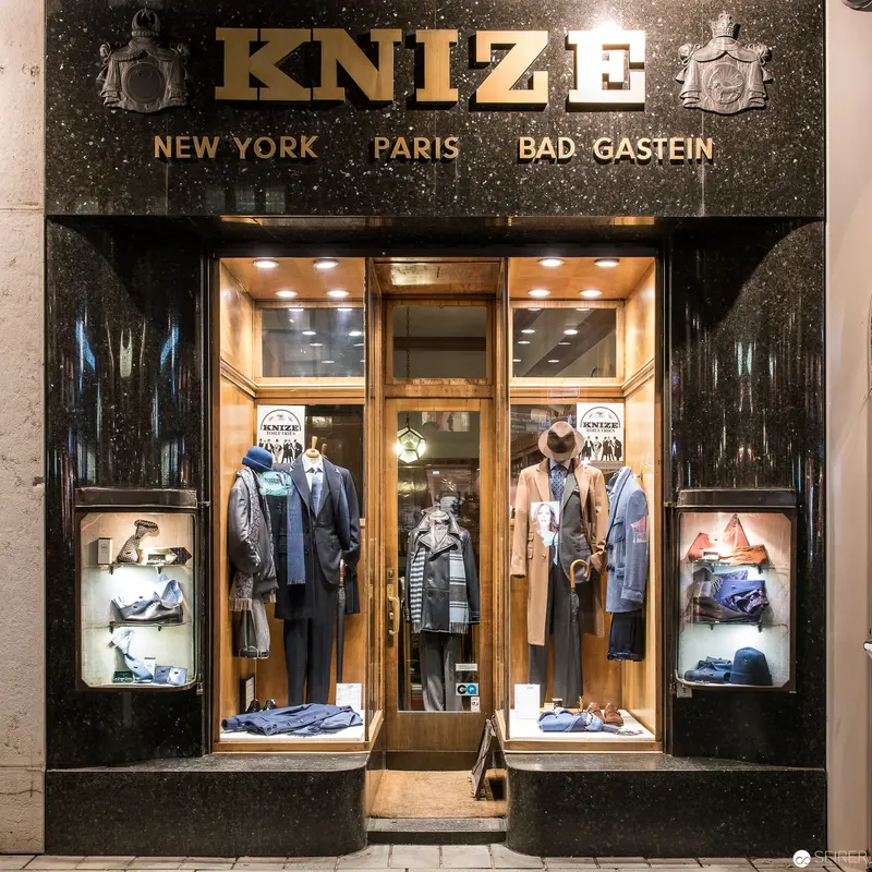 Knize Fashion Atelier Storefront Display in Elegant Urban Nighttime Setting