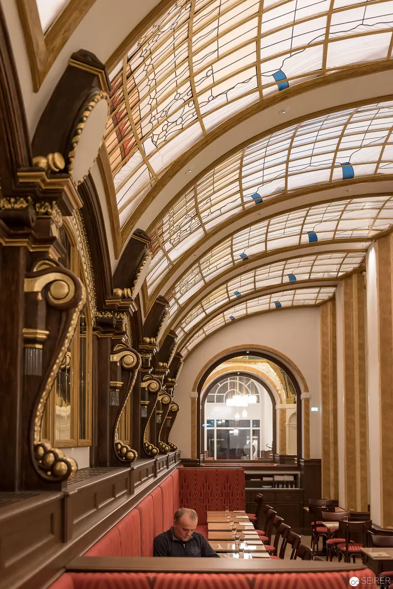 Elegant Art Nouveau Café Interior with Curved Glass Ceiling and Red Seating