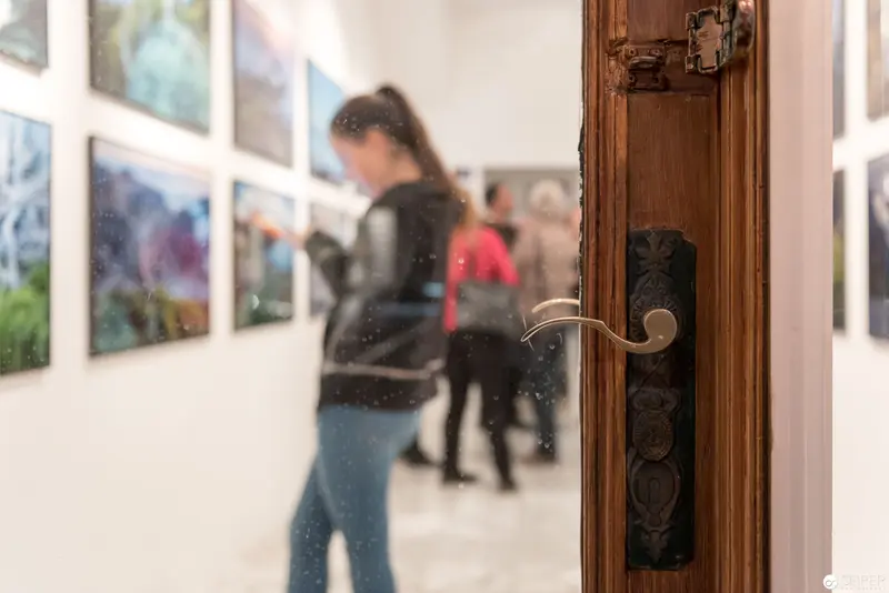 Wolf Hoffmann Vernissage: Gallery Interior with Wooden Door and Art Viewers