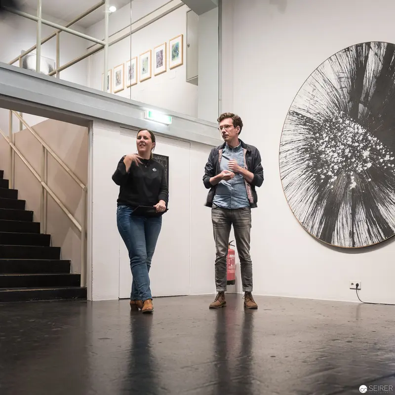 Alfons Schilling at Westlicht: Two Figures in Gallery Space with Radial Artwork