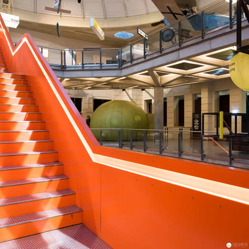 Vibrant Orange Staircase in Modernist Interior with Green Spherical Element