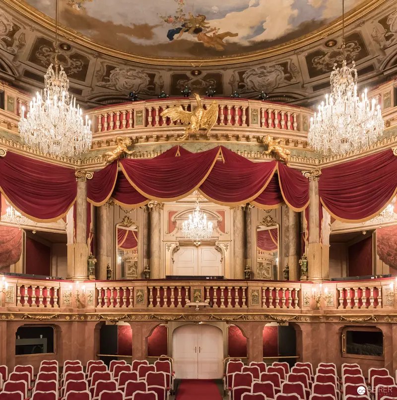 Opulent Baroque Theater Interior with Crimson Drapery and Crystal Chandeliers
