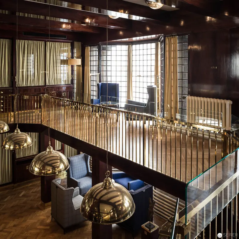 Gilded Mezzanine Interior with Brass Pendants and Architectural Metalwork