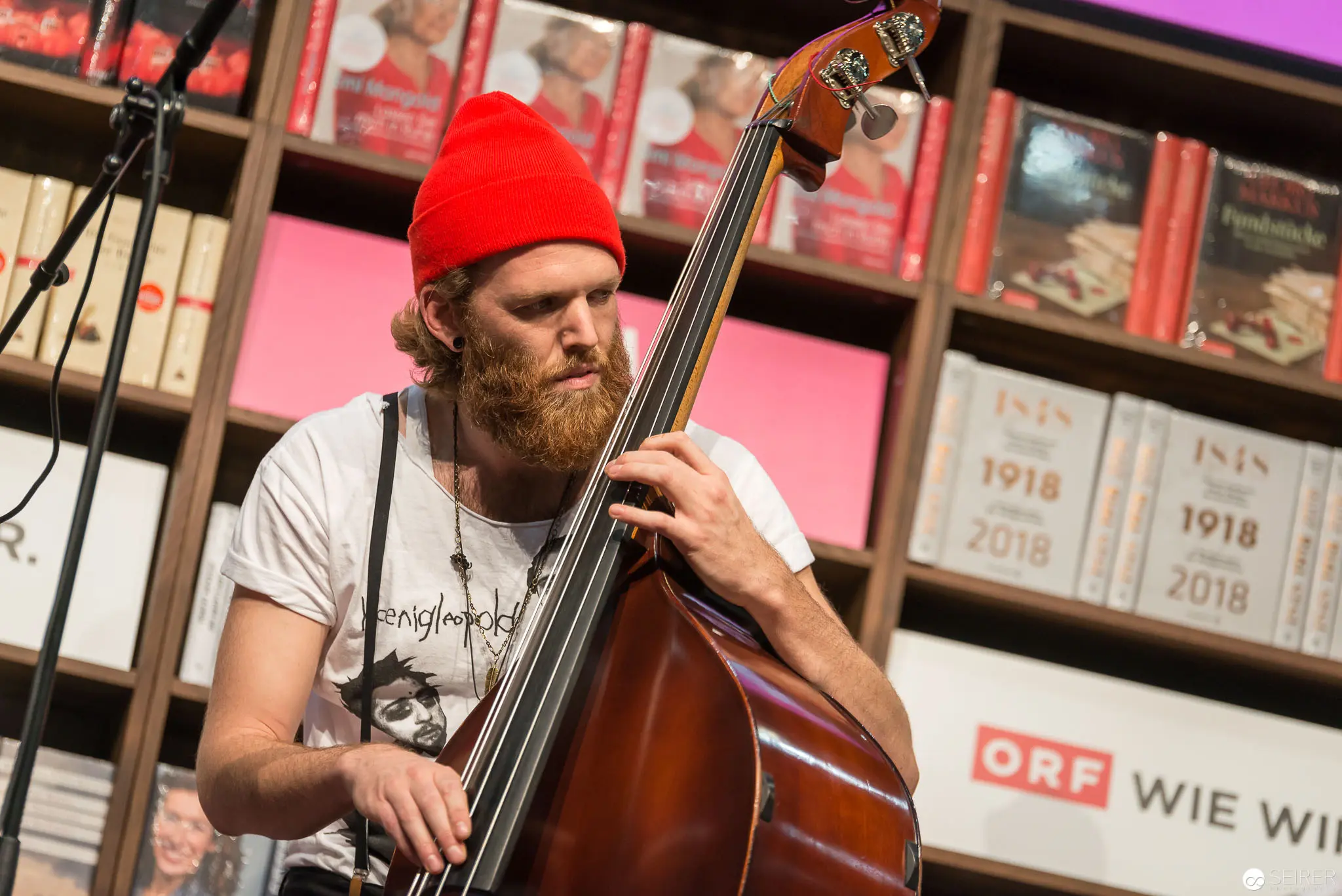 Musician in Red Beanie Performing on Upright Bass at Literary Event
