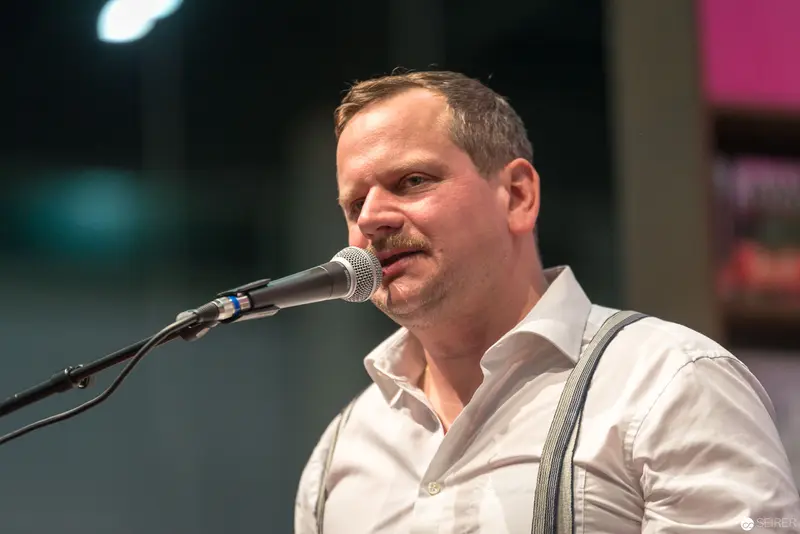 Performer in White Shirt Singing at Microphone with Emotional Expression