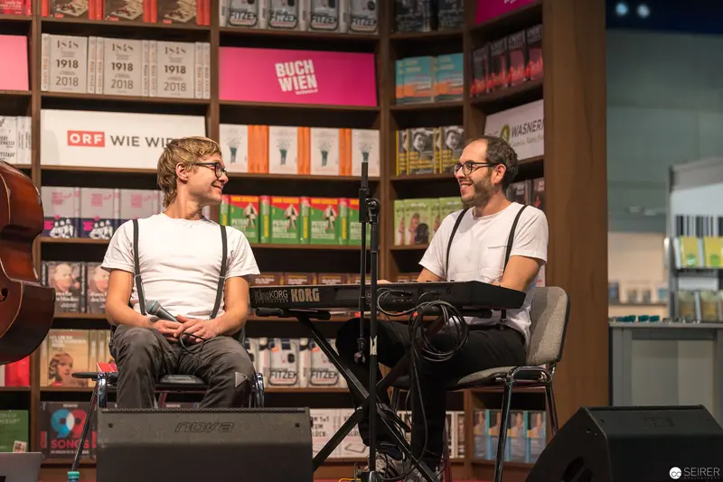 Two Musicians Performing at Buch Wien Literary Event with Musical Equipment