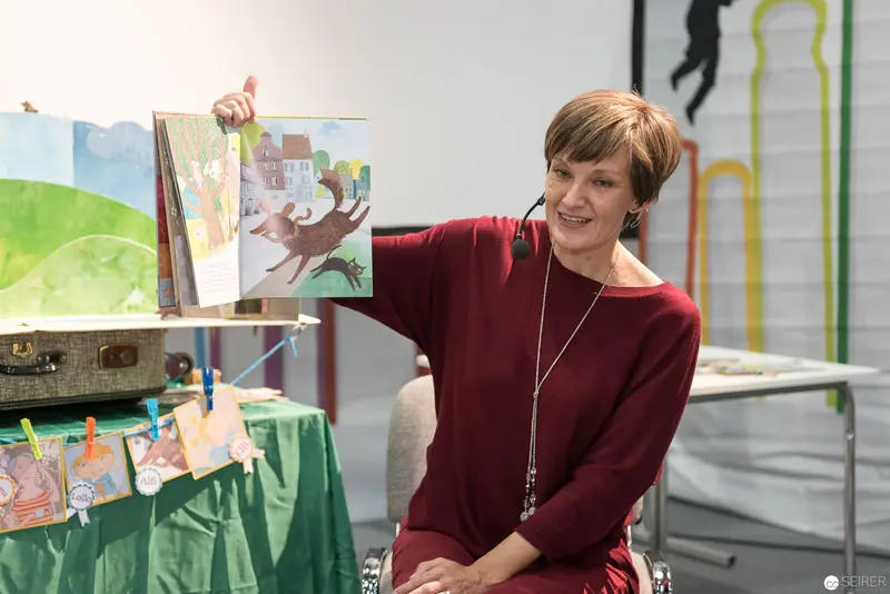 Book Wien 2017: Presenter Displaying Illustrated Children's Book with Vibrant Artwork