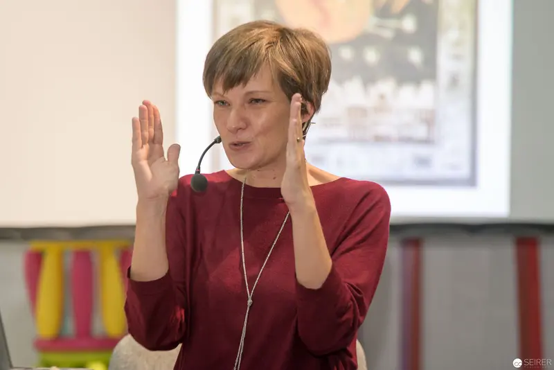 Woman in Red Presenting at Conference with Dynamic Hand Gestures