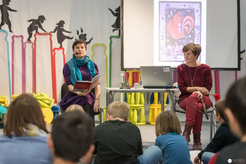 Lena Raubaum and Leonora Leitl Presenting a Reading to Young Audience