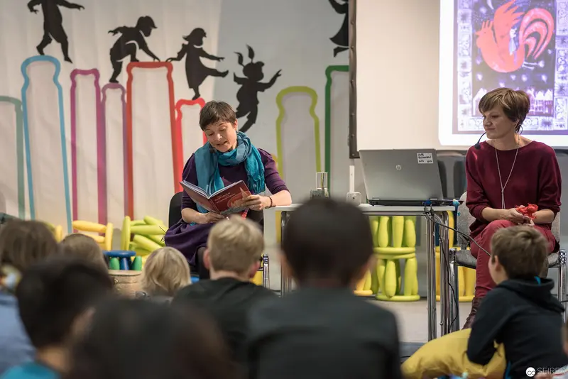Lena Raubaum Reading at Literary Event with Colorful Silhouette Backdrop