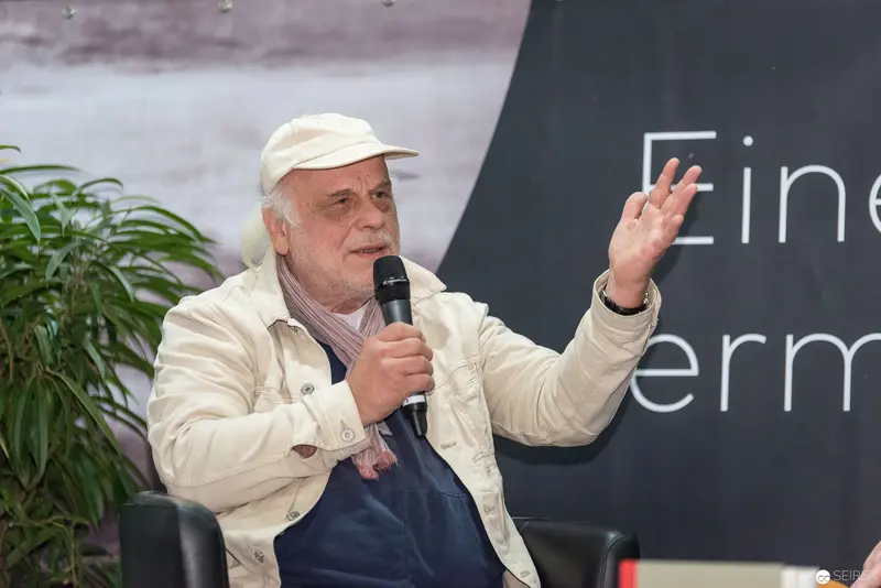 Elder Speaker at Book Event in Vienna Gesturing During Presentation