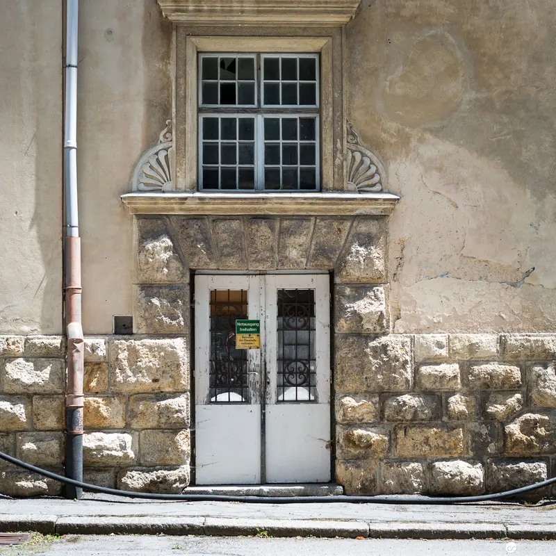 Stone Facade with Ornate Window and Weathered Doorway in Historic Architecture