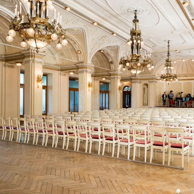 Elegant Ceremonial Hall with Ornate Chandeliers and Arranged Seating