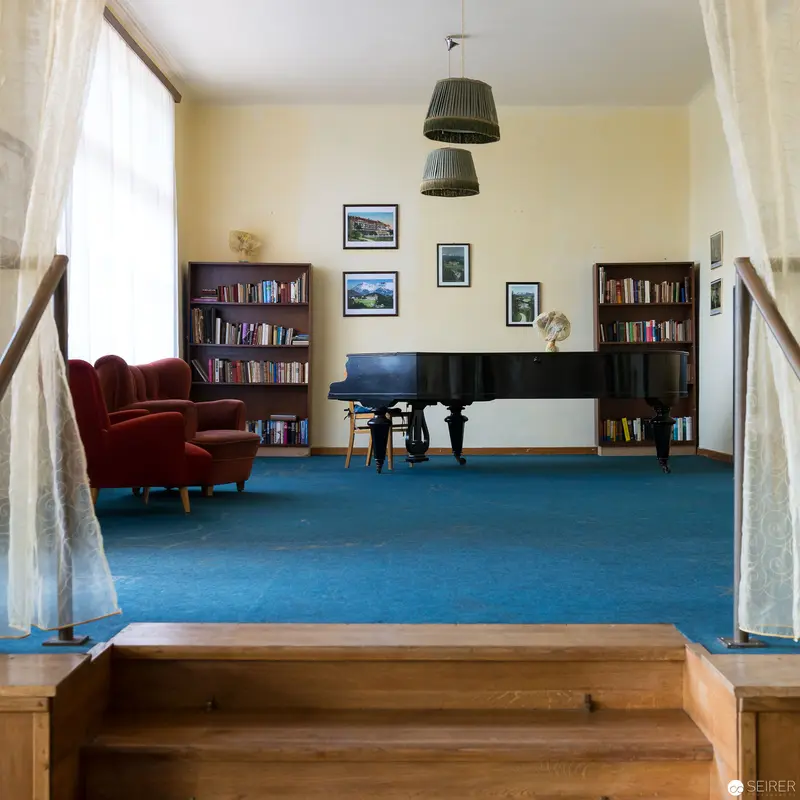 Minimalist Interior with Grand Piano, Blue Carpet, and Bookshelves in Soft Light