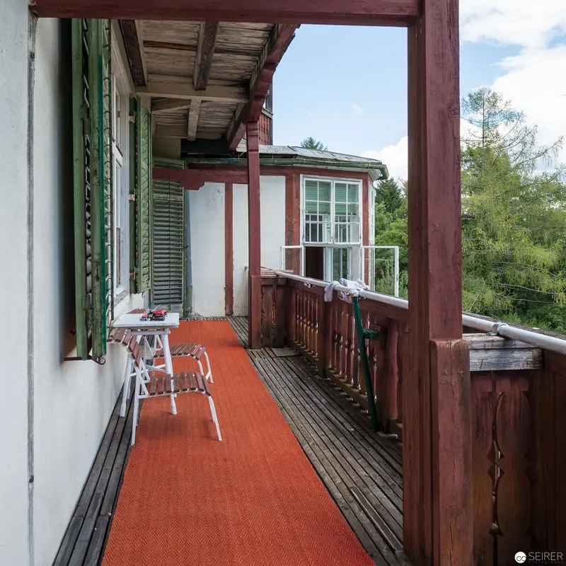 Rustic Balcony with Orange Runner and Wooden Architectural Details