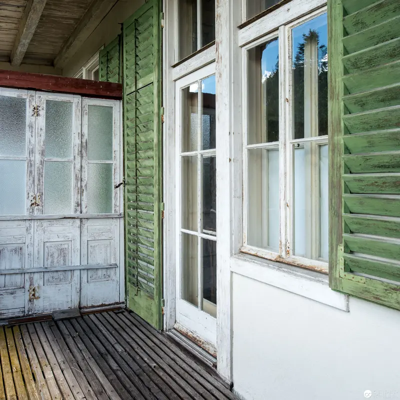 Weathered Coastal Porch with Faded Green Shutters and Textured Wooden Deck