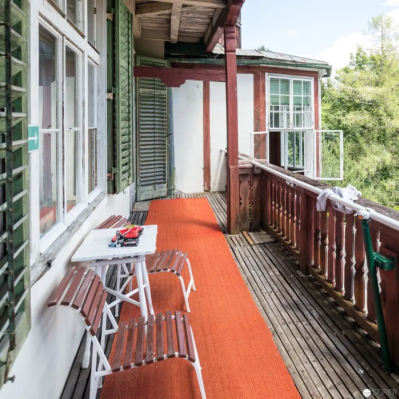 Rustic Balcony Interior with Orange Carpet and Vintage Wooden Furniture