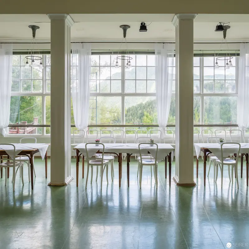 Minimalist Dining Hall with Large Windows and Pale Wooden Chairs
