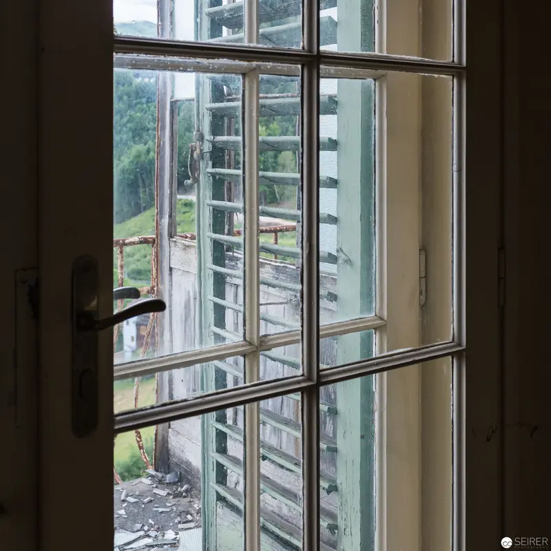 Interior View Through Weathered Multi-Paned Window Revealing Architectural Decay