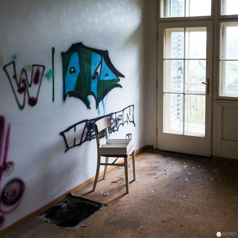 Abandoned Interior with Graffiti and Wooden Chair by Weathered Window