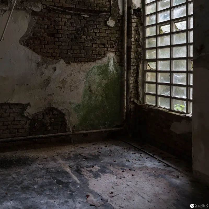 Derelict Interior with Fractured Wall and Gridded Window in Abandoned Space