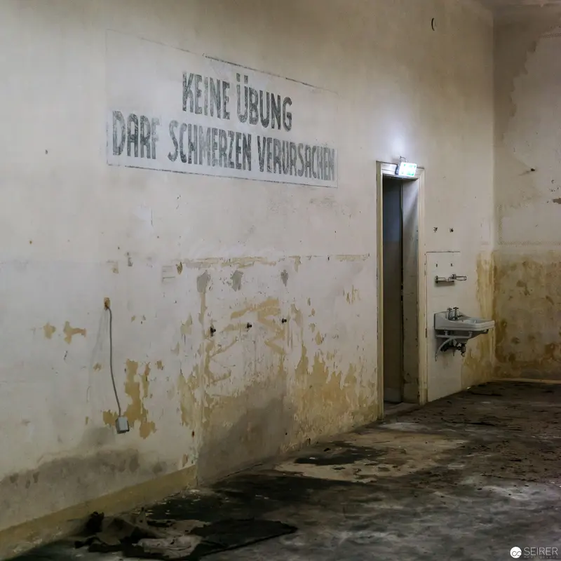 Abandoned Institutional Space with Faded German Warning Sign and Deteriorating Walls