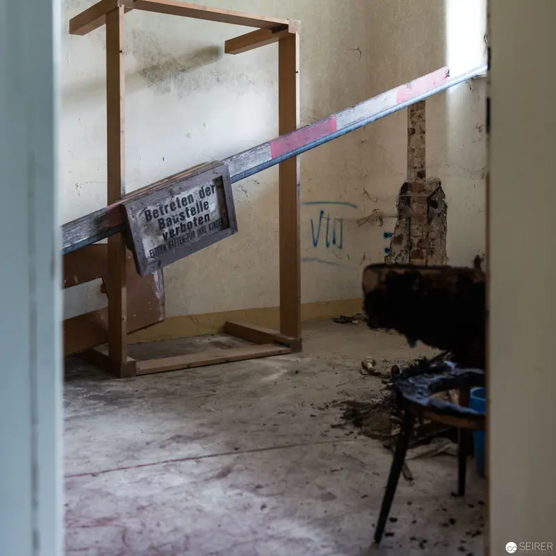 Decaying Interior with Wooden Frame and Warning Sign in Abandoned Space