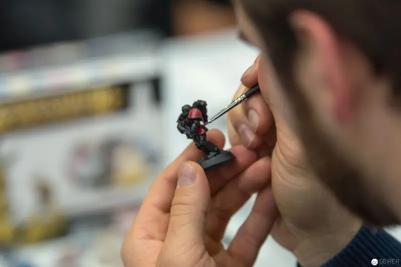 Miniature Painting Technique: Artist Meticulously Detailing Small Figurine with Fine Brush