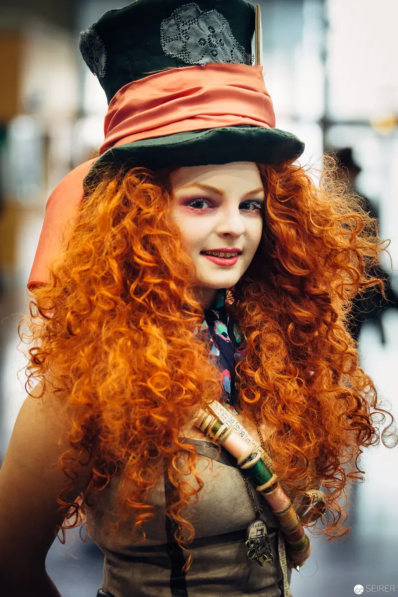 Costumed Performer with Vibrant Orange Curls in Theatrical Mad Hatter Attire