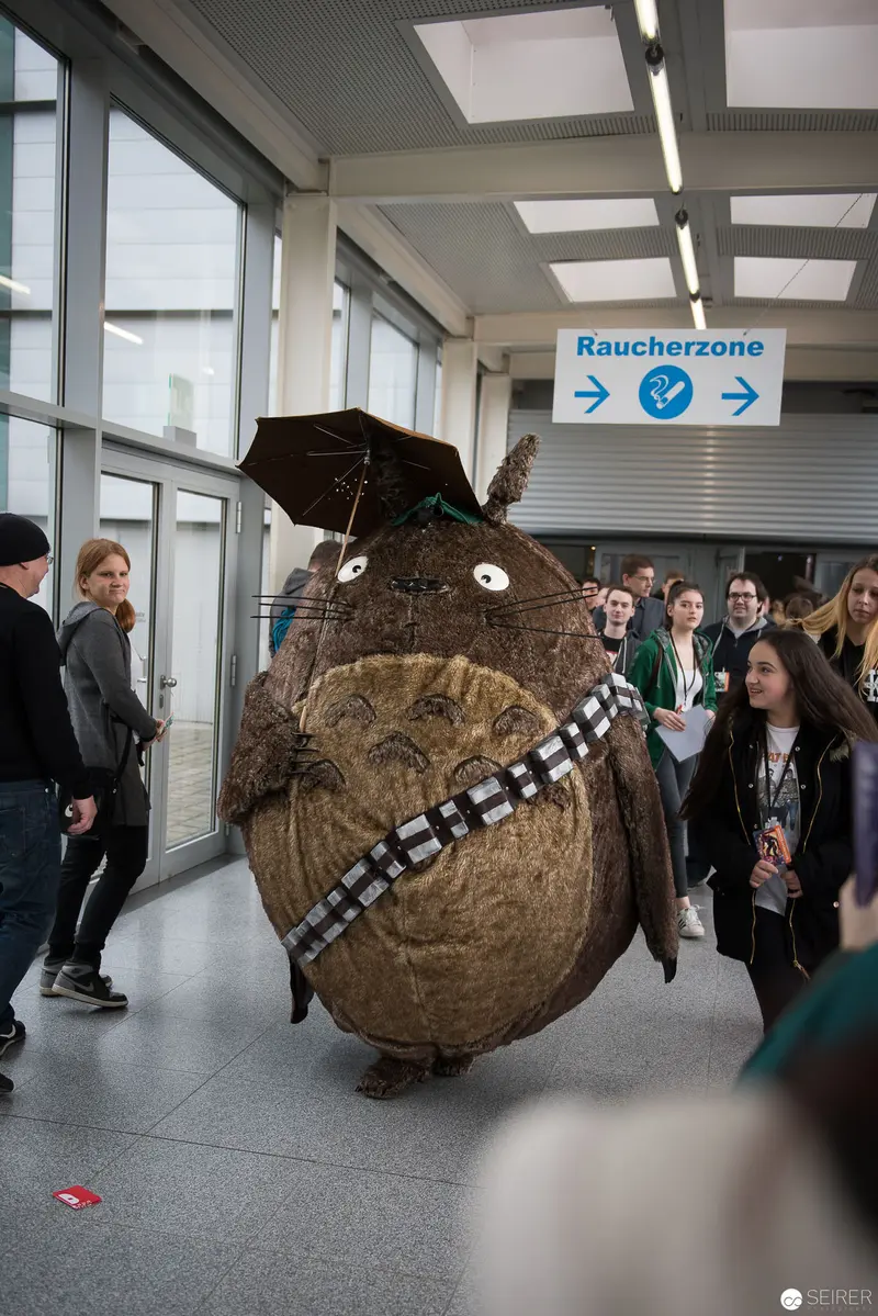 Costumed Chewbacca Mascot Navigating Indoor Corridor with Bystanders