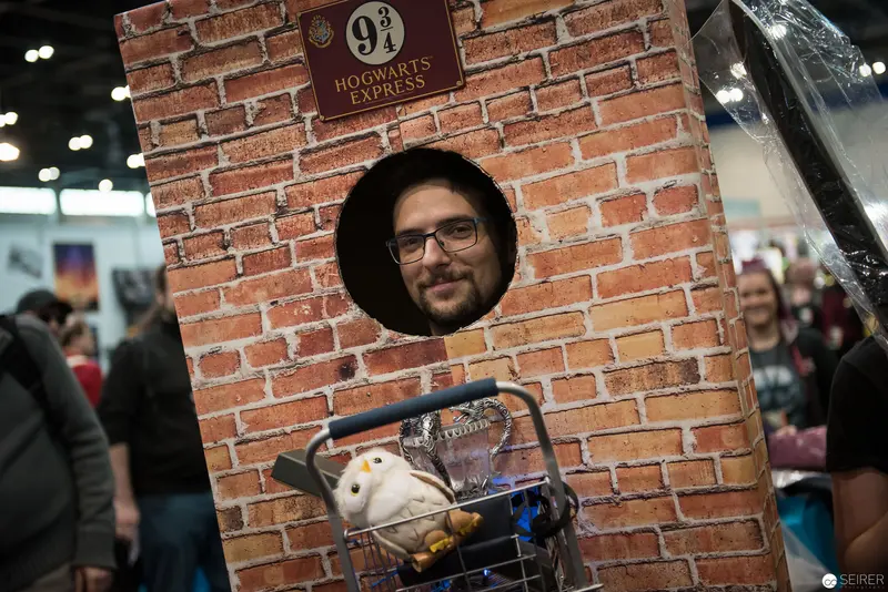Harry Potter Fan Posing at Platform 9¾ Themed Photobooth During Convention