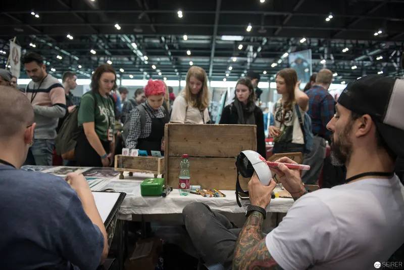 Indoor Exhibition Scene with Artists and Crafted Wooden Display Station