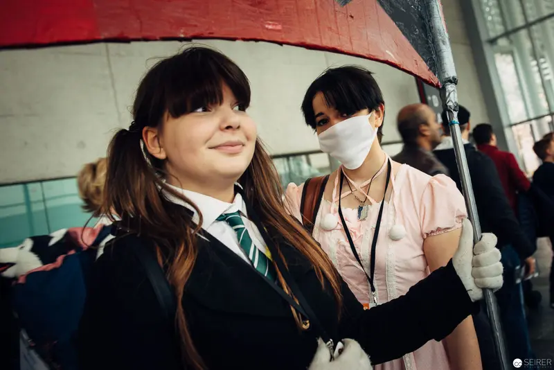 School Commute During Pandemic: Students Under Red Umbrella in Urban Transit